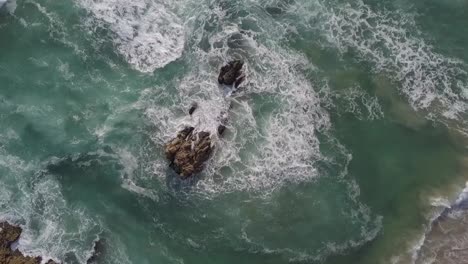 Brilliant-green-waves-meet-rocks-near-shore-and-create-dramatic-chaos