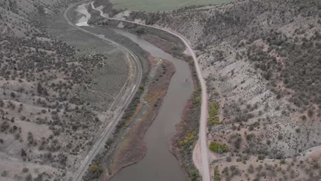 Sedan-driving-along-the-Colorado-River-on-a-remote-road