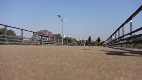 rear-view-of-man-walking-on-the-overpass-and-cyclist-crossing-it-at-speed