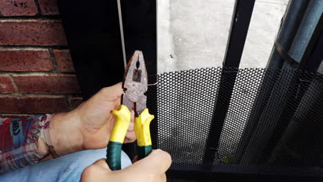 Mann-Repariert-Ein-Gitternetz-Für-Eine-Haustiertür-Mit-Einem-Draht