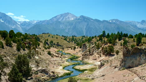 Establishing-Landscape-Shot-of-Hot-Creek-Beneath-Towering-Eastern-Sierra-Mountains-on-Sunny-Day