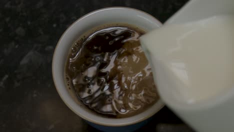 Pouring-milk-into-a-mug-of-black-instant-coffee-in-slow-motion