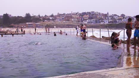 Tourists-enjoying-a-swim-and-the-view-of-the-Bronte-Beach-in-Australia-with-the-peaceful-city-of-Sydney-in-the-distance---Slow-motion