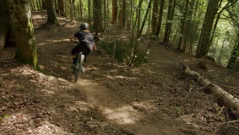 Mountain-biker-lands-from-jump-and-rides-through-a-dusty-corner