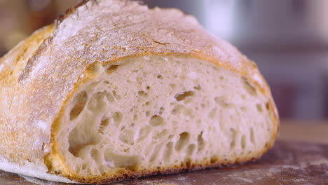 Sourdough-Bread-Loaf-On-Cutting-Board---macro,-pan-shot