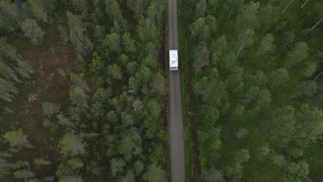 A-view-from-above,-showing-a-motorhome-driving-trough-a-green-forest