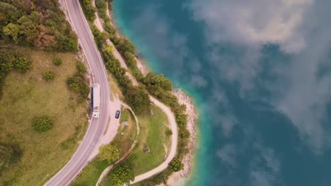 Aerial-"bird-eye"-view-of-Ledro-lake-with-a-street-and-car-and-truck-that-passing-through