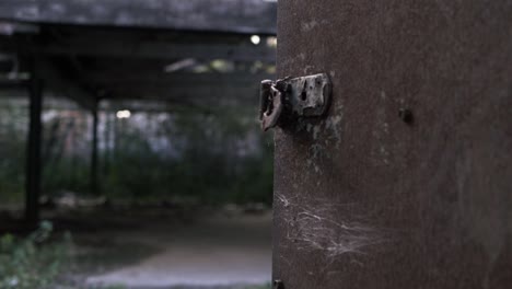 View-of-derelict-building-through-rusty-old-door-medium-tilting-shot
