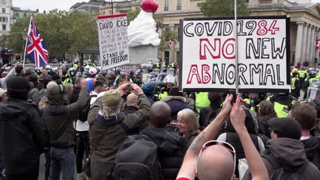 Coronavirus-conspiracy-protestors,-one-holding-a-“Covid-1984,-no-new-abnormal”-placard,-oppose-riot-police-in-front-of-Heather-Phillipson’s-The-End-art-commission-on-Trafalgar-Square’s-fourth-plinth