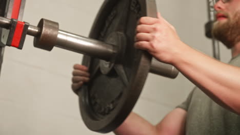 Man's-hands-sliding-45-pound-weight-plate-off-of-barbell,-Medium-Shot,-Low-Angle,-Slow-Motion