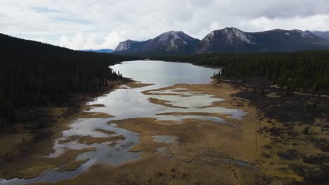 Johnson-Range-lake-on-cloudy-day-with-shallow-lake-edge,-aerial-drone
