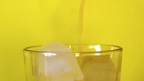 Gießen-Sie-Frischen-Orangensaft-In-Ein-Glas-Mit-Eiswürfeln