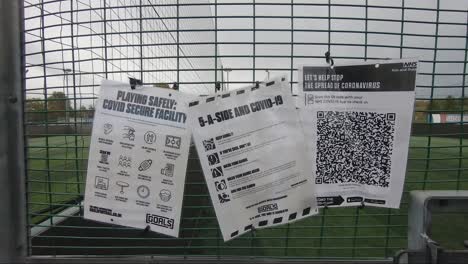 Covid-Safe-Signs-Along-With-Contact-Track-And-Trace-QR-Code-App-Hanging-On-Fence-At-Goals-Ruislip