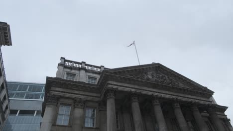 Bandera-Inglesa-Sobrevolando-La-Mansión-De-Londres-En-Un-Día-Nublado-Desde-Abajo