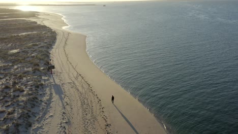 One-person-walking-alone-on-beach-on-deserted-island-in-Portugal-at-sunset