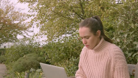 Female-working-on-a-laptop-in-a-park-stressed