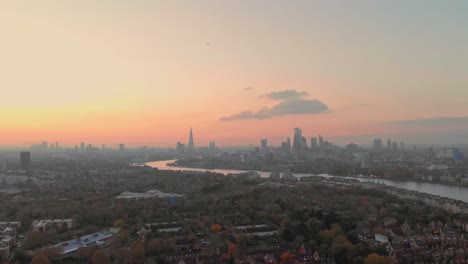 Dolly-forwards-drone-shot-over-Canada-water-London-towards-city-centre-sunset