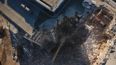 Aerial-drone-view-of-claw-Excavator-demolishing-a-concrete-building-or-apartment