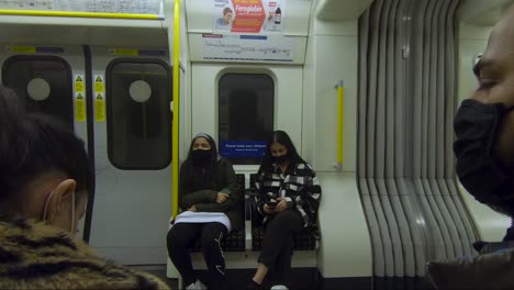Familia-Sentada-Una-Frente-A-La-Otra-Usando-Máscaras-Faciales-En-El-Tren