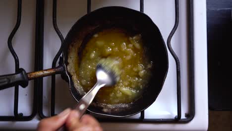 Chef-making-homemade-caramel-sauce,-mixing-butter-and-sugar-over-hot-stove