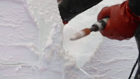 Ice-Sculptor-brushing-away-shavings-with-his-hand-to-reveal-clean-surface,-Slow-Motion