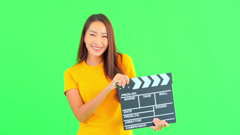 Smiling-Asian-woman-with-yellow-t-shirt-holds-clapperboard