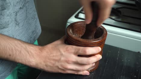 Man-Grinding-Spices-And-Black-Pepper-On-Wooded-Mortar-With-Pestle