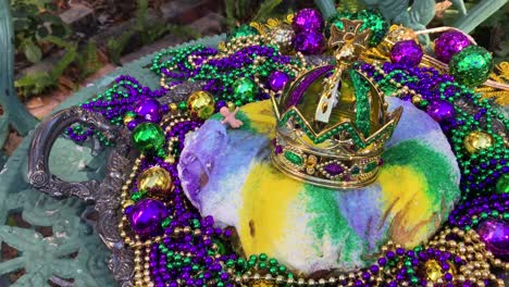 outdoors-Mardi-Gras-king-cake-with-crown-and-tiny-baby-surrounded-by-colorful-beads