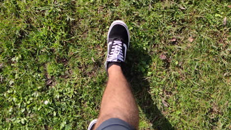 Slow-Motion-Of-A-Man's-Feet-In-Vans-Sneakers-Walking-On-Grassy-Ground---top-down,-handheld