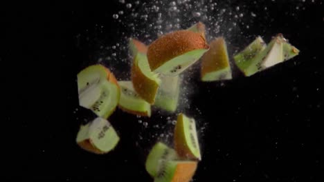 Kiwi-Pieces-Falling-into-Water-Super-Slowmotion,-Black-Background,-lots-of-Air-Bubbles,-4k240fps