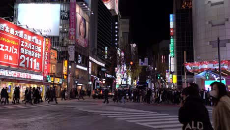 Crowds-of-people-wearing-facemasks-crossing-street-in-Tokyo-at-night
