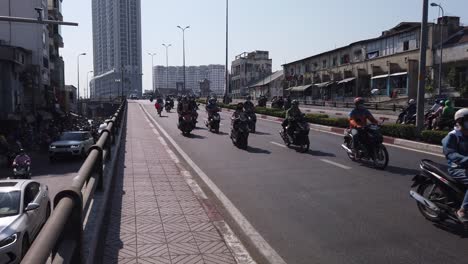Vietnam,-Ho-chi-Minh-City,-bust-motorcycle-traffic-on-a-bridge-featuring-modern-high-rise-buildings-and-older-french-coolonial-building-on-a-sunny-day