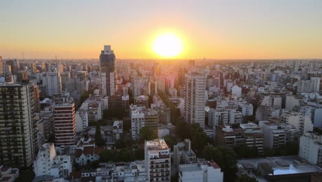 Aerial-pan-right-of-Belgrano-neighborhood-buildings-and-skyscrapers-at-sunset-with-bright-sun,-Buenos-Aires,-Argentina