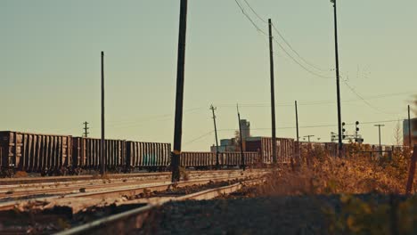 Freight-Train-Cargo-Cars-Parked-at-Abandoned-Industrial-City-Railway-Yard-as-Birds-Fly-overhead-During-Golden-Hour-Cinematic-4k