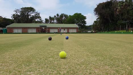 Men-playing-lawn-bowls-on-a-sunny-calm-day-at-a-coastal-town