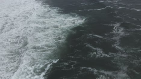 Weiße-Wellen-Krachen-Gegen-Eine-Felsige,-Zerklüftete,-In-Nebel-Gehüllte-Küste,-Luftaufnahme