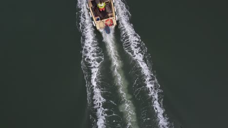 A-still-top-down-drone-shot-of-a-small-workboat-powering-upstream-leaving-a-wake-behind