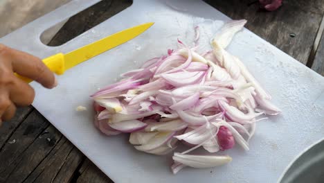 Close-up-chopping-onions,-Female-hands-cut-onions-with-yellow-knife-on-white-board