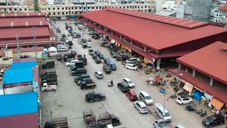 Aerial-footage-of-the-local-food-market-store-building-car-and-truck-parking-and-people-walk-around-for-shopping-fresh-fruit-and-vegetable-in-the-early-morning