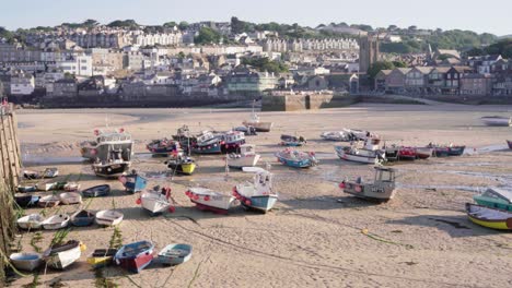 Fishing-Boats-Moored-On-The-Harbor-During-Lowtide-With-St-Ives-Town-In-The-Background-In-Cornwall,-England,-United-Kingdom