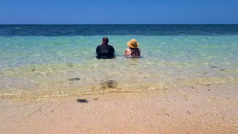 Couple-Sitting-Together-With-Ocean-Waves-Gently-Going-Past-Them-Near-Beach