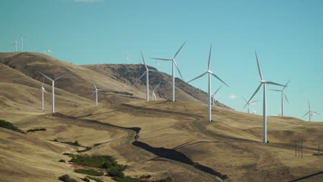 Windmills-turn-slowly-on-a-golden-brown-hillside-against-an-azure-blue-sky
