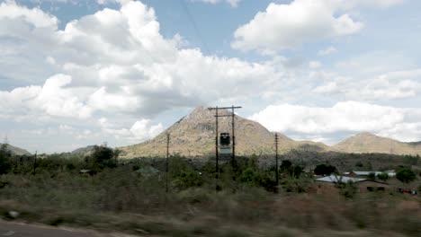 Traveling-along-a-highway-in-Malawi-Africa-with-a-town-and-vehicles-passing,-View-from-vehicle-advancing