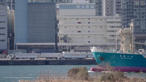 Tanker-Ship-Sailing-In-Tokyo-Bay-With-Warehouse-Facility-In-Background-In-Tokyo,-Japan