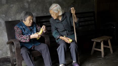 Two-old-lady-friends-sharing-a-funny-moment-eating-a-banana