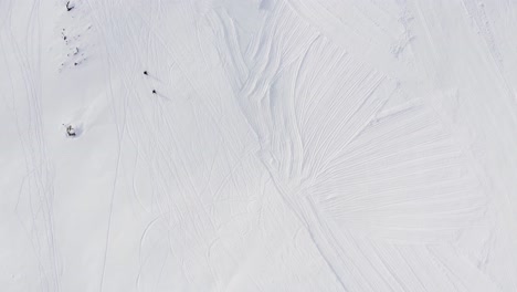 Aerial-top-down-shot-Of-Two-People-Walking-On-Snowy-Road-up-the-mountain