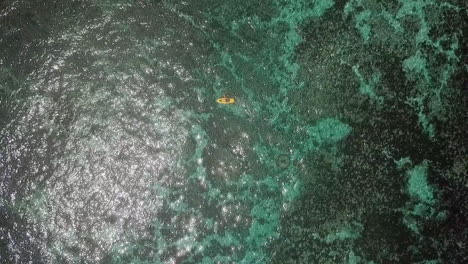 AERIAL-PLAN-VIEW-SLOW-MOTION,-a-man-in-a-kayak-in-a-turquoise-sea