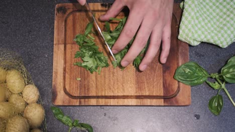 Young-male-cutting-celery-in-his-kitchen-on-top-of-a-cutting-board-with-a-sharp-knife
