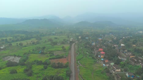 Fallende-Drohne-Schoss-über-Ländliche-Indische-Straßenhügel-Im-Hintergrund-Grün