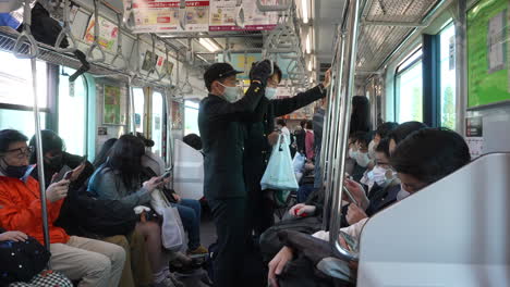 Straphanger-–-Zwei-Highschool-Schüler-Mit-Gesichtsmaske-In-Einem-überfüllten-Zug,-Der-In-Der-Stadt-Tokio,-Japan,-Unterwegs-Ist
